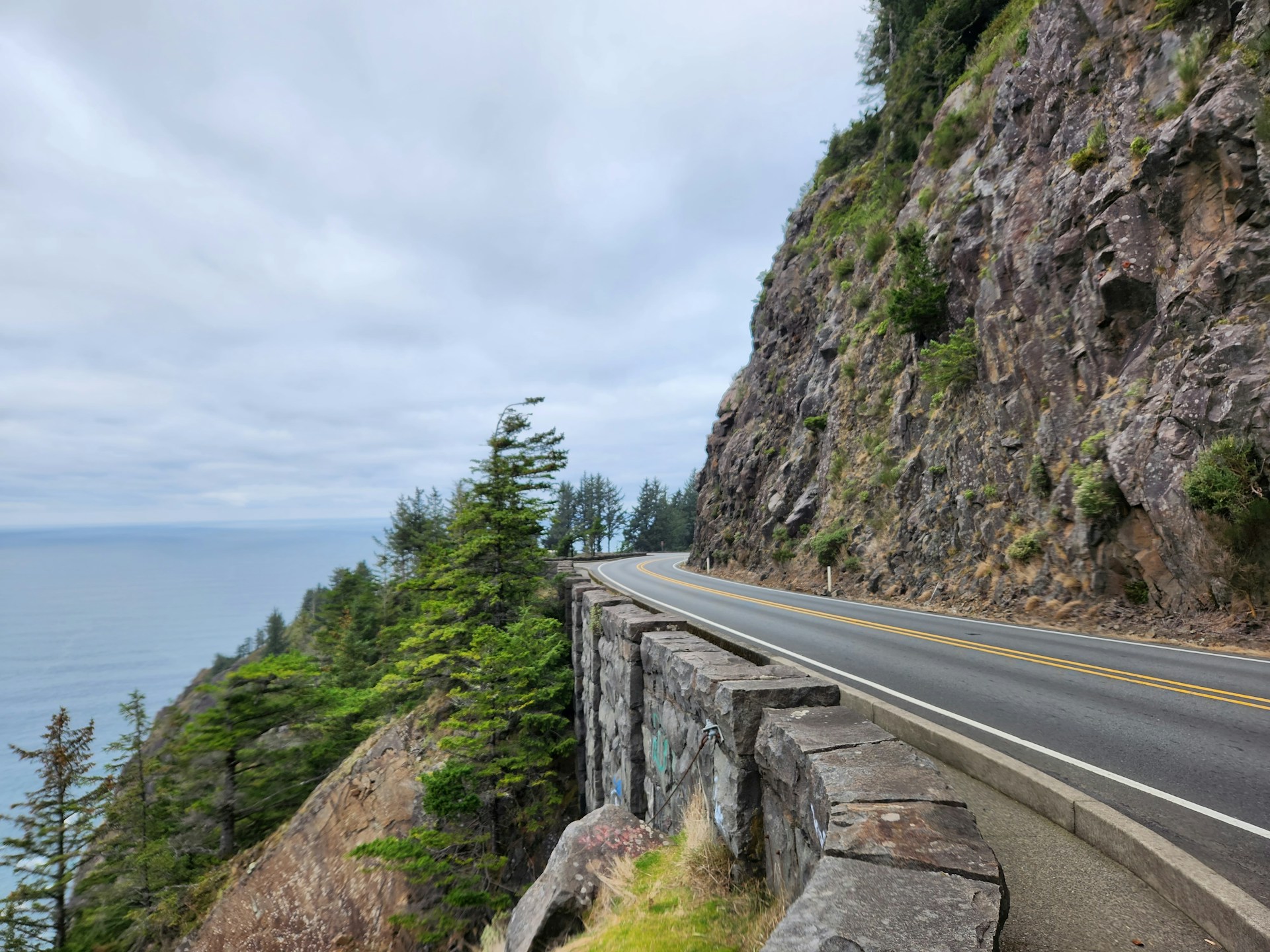 A stretch of Pacific Coast Highway hugging the coastline between hills and trees