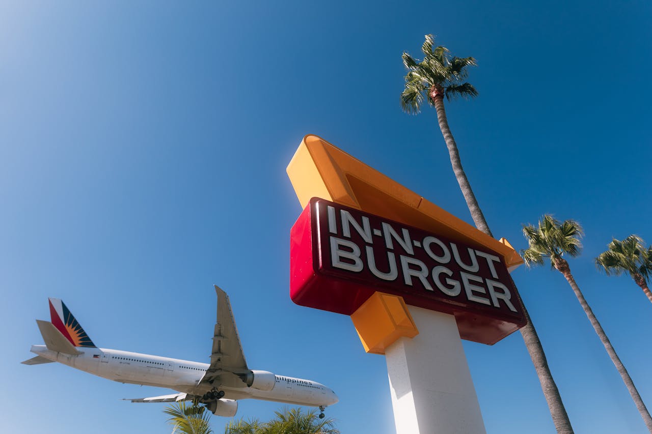 A plane flying past a sign for Los Angeles’s iconic In-N-Out Burger