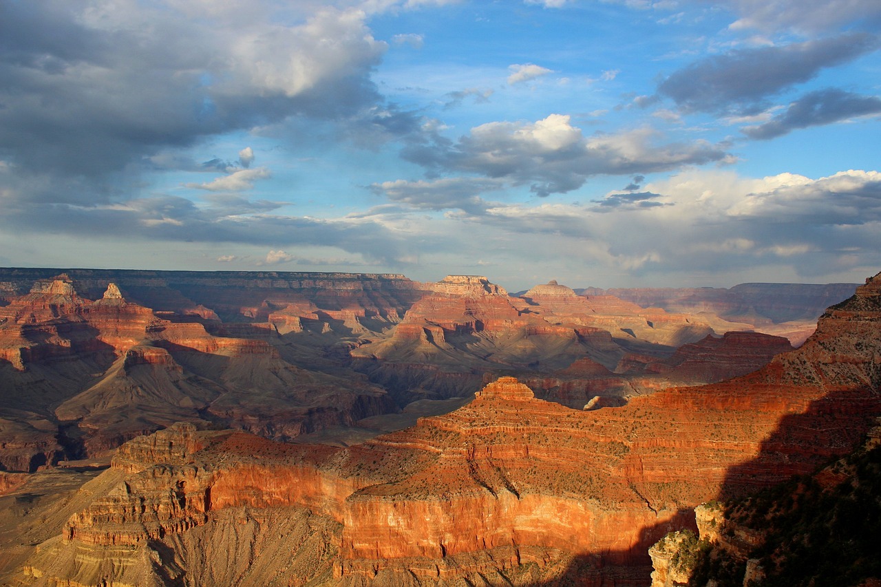 The vibrant colors of the Grand Canyon with clouds and blue sky overhead